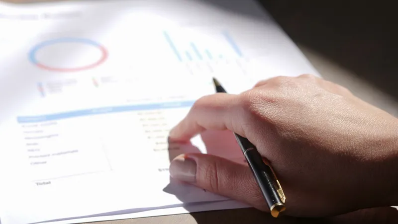 Basılı bir finansal raporu inceleyen bir el