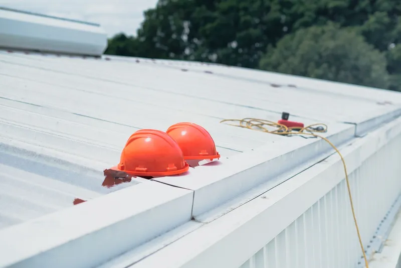 Two hard hats resting on the edge of a roof on a construction site
