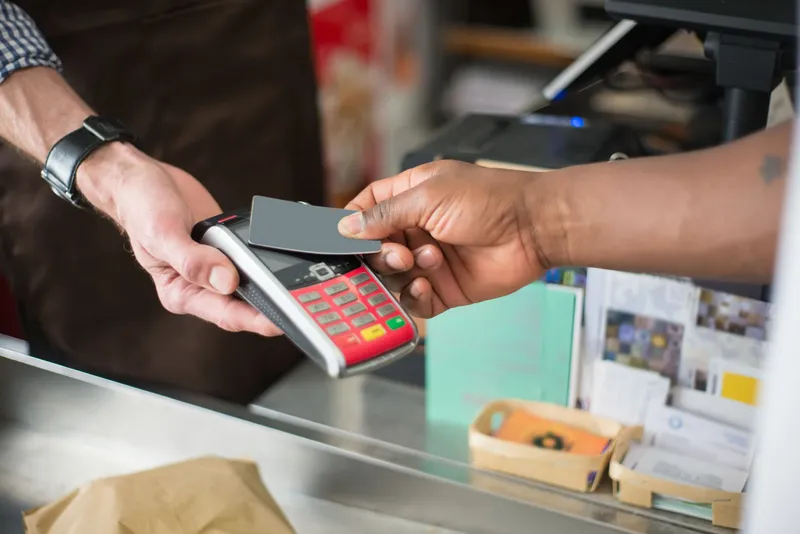 Hands completing a contactless card payment at a shop counter