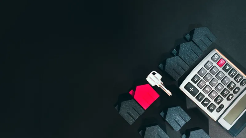 A house-shaped keyring and key resting on a calculator