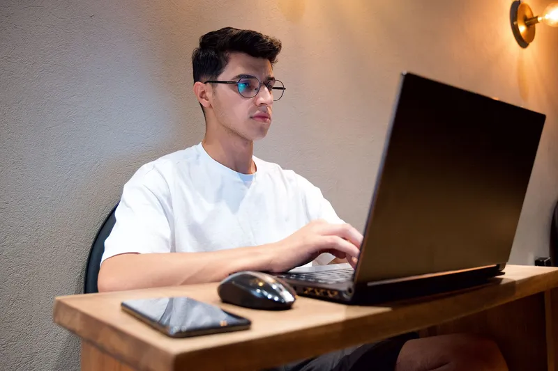 A freelancer working at a laptop on a wooden desk